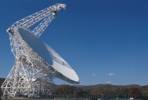 Immense parabole blanche du Green Bank Telescope entourée de collines boisées.
