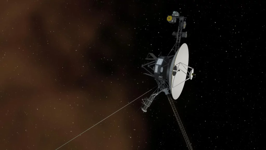 Sonde Voyager vue en plan rapproché: grande antenne parabolique blanche, structure métallique et longs booms, sur fond d'étoiles et de nuages de gaz brunâtres de l'espace lointain.
