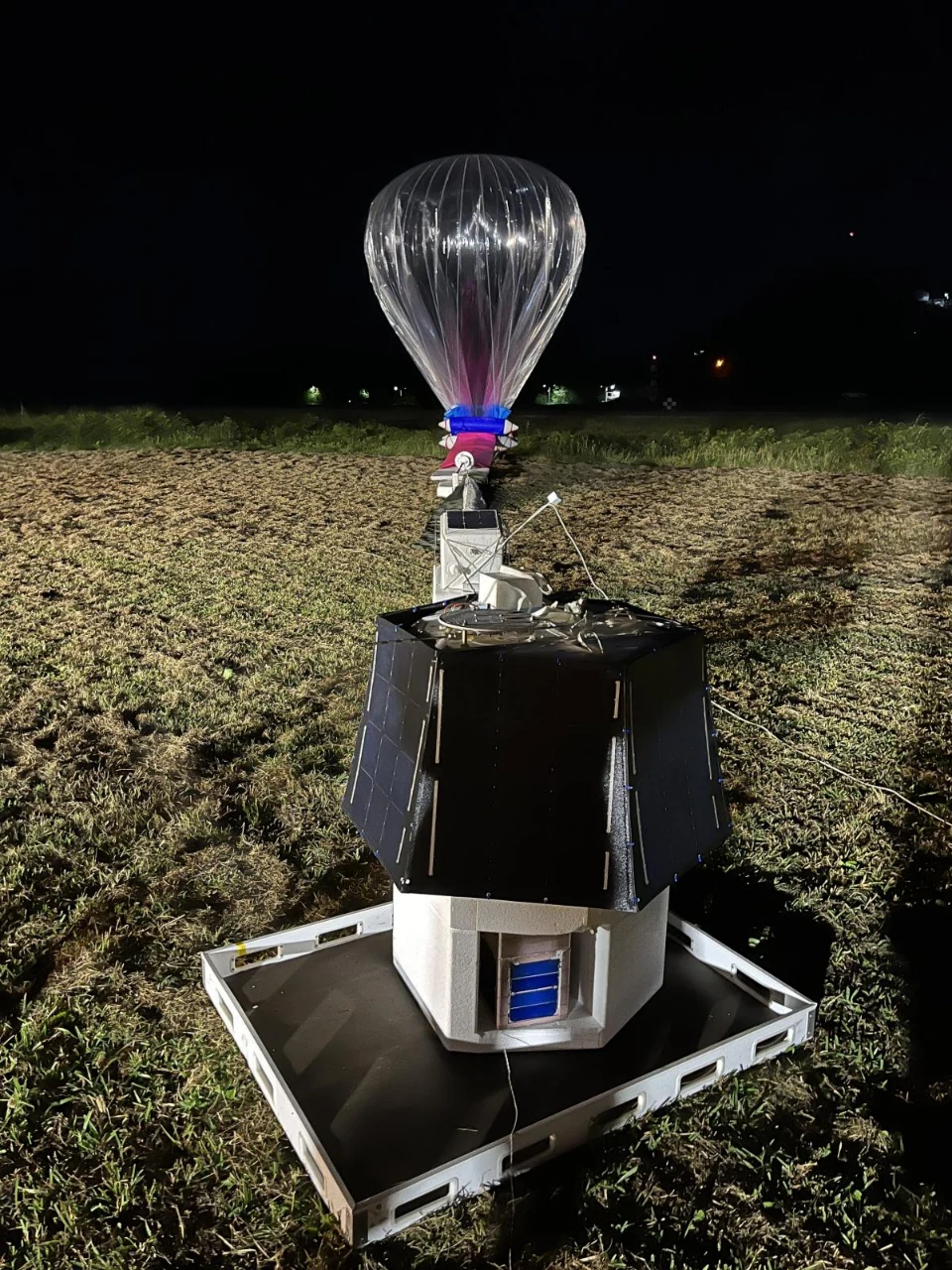 Ballon Strateole‑2 préparé pour un lâcher nocturne, avec deux nacelles alignées au sol : la nacelle scientifique au premier plan et la nacelle de servitude près du ballon.