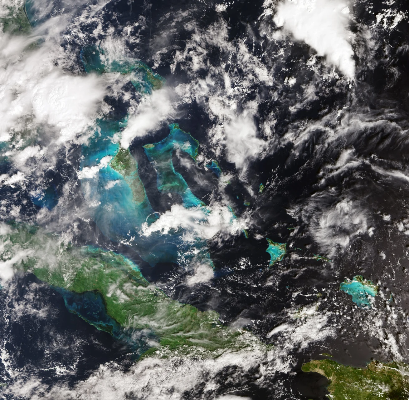 Vue satellitaire de Cuba et des Bahamas, entourés d’eaux turquoise et bleu foncé.