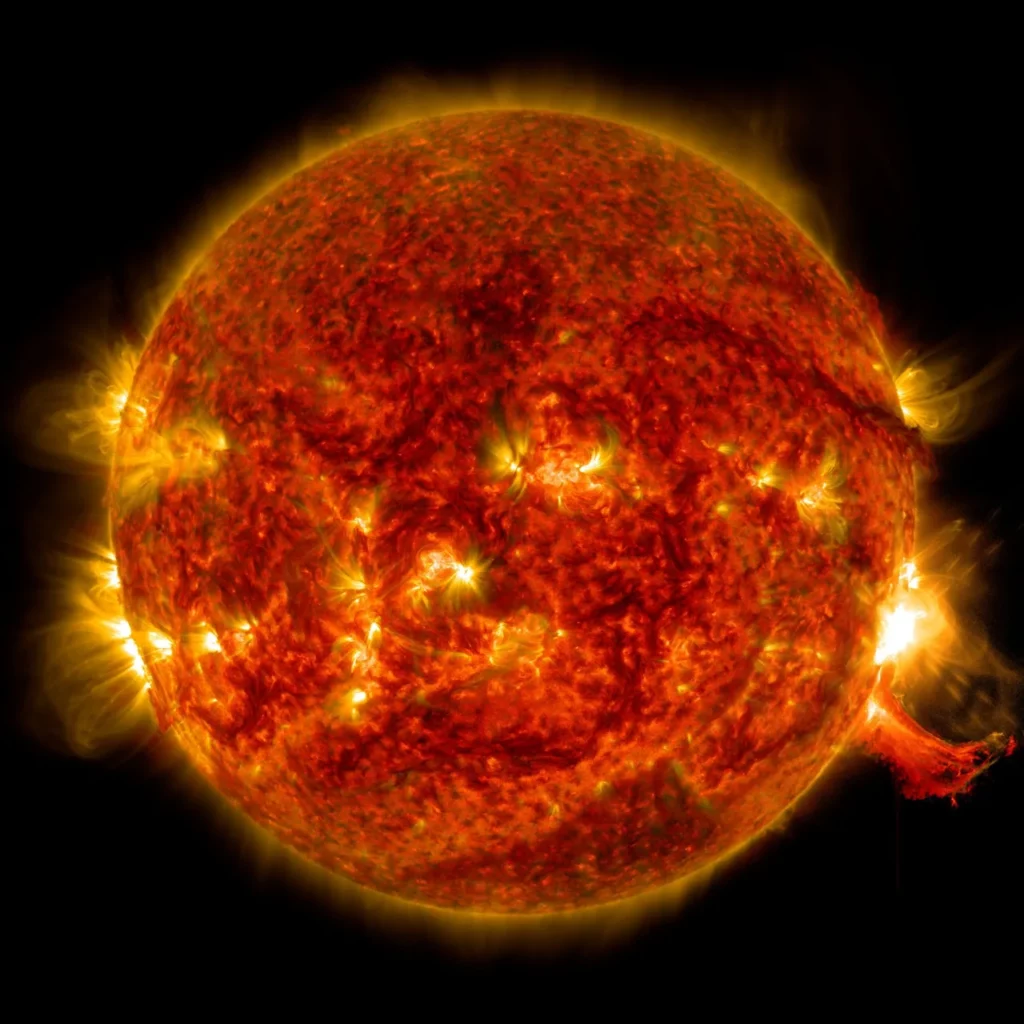 Disque solaire en lumière ultraviolette extrême montrant des régions actives très lumineuses, une protubérance éruptive au limbe droit et la couronne solaire environnante (image composite SOHO).
